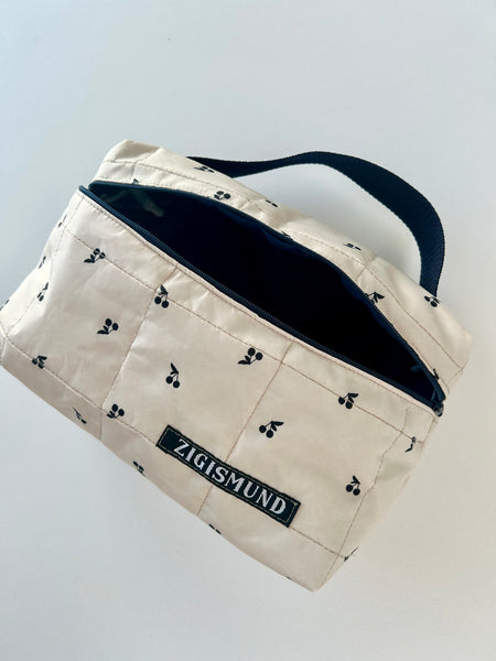 Skøn og rummelig toilettaske i råhvid med sorte kirsebær.