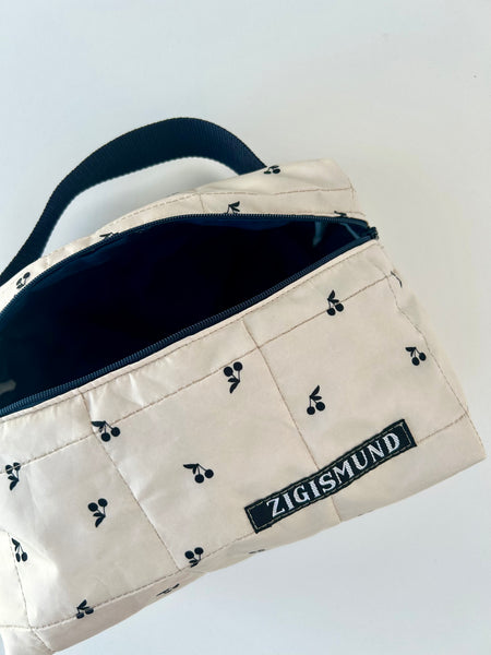 Skøn og rummelig toilettaske i råhvid med sorte kirsebær.