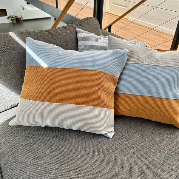 Pudebetræk i gyldenbrun, pastel blå og mørk kit. Pastel blå bagside.