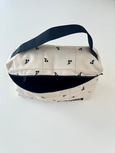 Skøn og rummelig toilettaske i råhvid med sorte kirsebær.