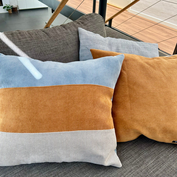 Pudebetræk i gyldenbrun, pastel blå og mørk kit. Pastel blå bagside.