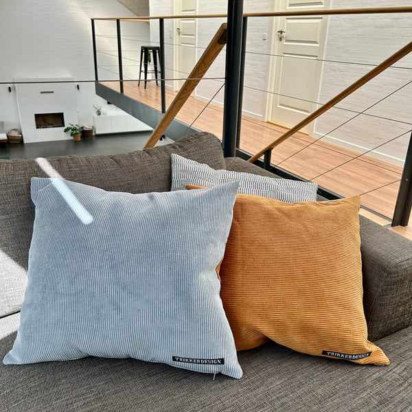 Pudebetræk i gyldenbrun, pastel blå og mørk kit. Pastel blå bagside.