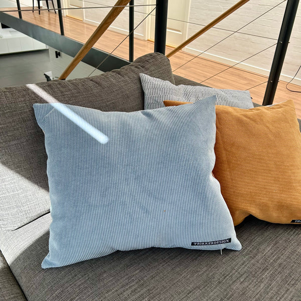 Pudebetræk i gyldenbrun, pastel blå og mørk kit. Pastel blå bagside.