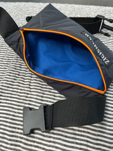 Bæltetaske i charcoal med orange lynlås.