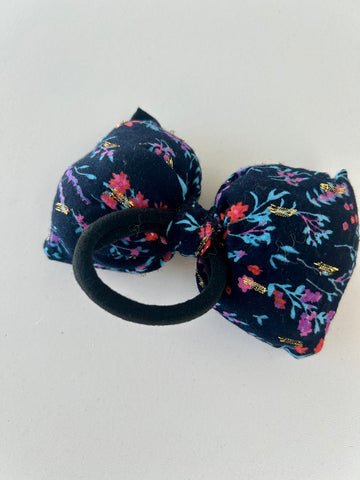 Stor fluffy sløjfe med blomster og guld detaljer.