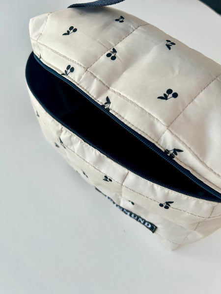 Skøn og rummelig toilettaske i råhvid med sorte kirsebær.