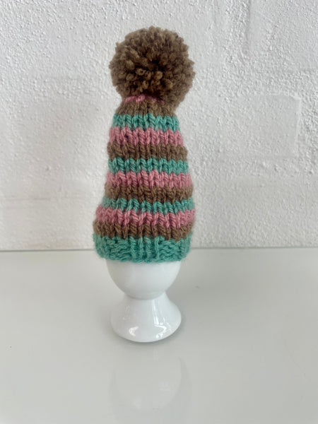 Æggevarmer aka Nissehue i lyserød, turkis og brun strik og med pom pom.