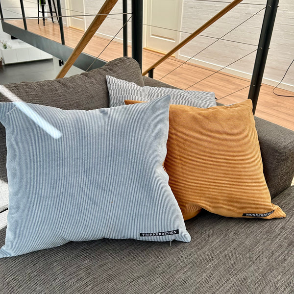 Pudebetræk i gyldenbrun, pastel blå og mørk kit. Pastel blå bagside.