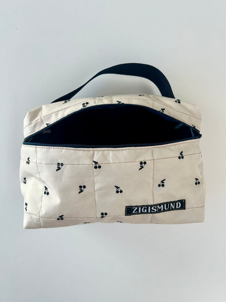 Skøn og rummelig toilettaske i råhvid med sorte kirsebær.