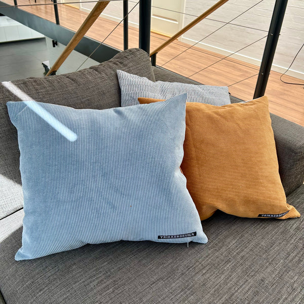 Pudebetræk i gyldenbrun, pastel blå og mørk kit. Pastel blå bagside.