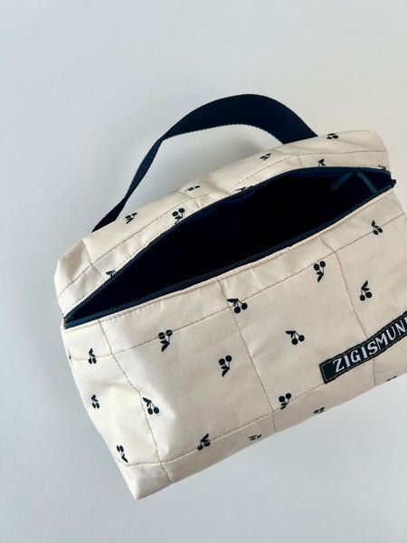 Skøn og rummelig toilettaske i råhvid med sorte kirsebær.