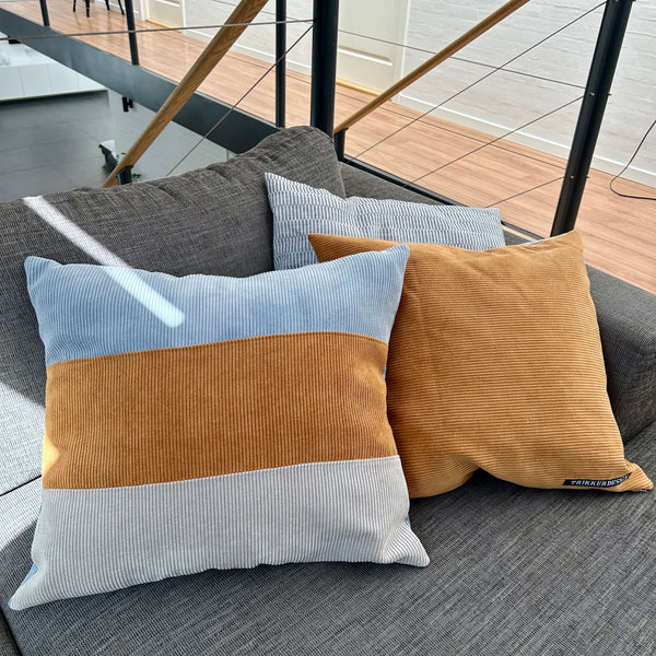 Pudebetræk i gyldenbrun, pastel blå og mørk kit. Pastel blå bagside.