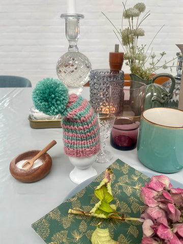 Æggevarmer ska Nissehue i lyserød og turkis strik med pom pom.