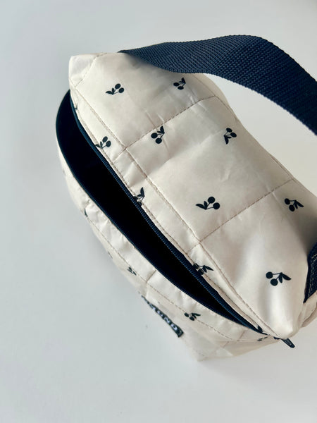 Skøn og rummelig toilettaske i råhvid med sorte kirsebær.