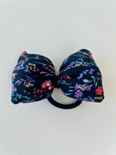 Stor fluffy sløjfe med blomster og guld detaljer.