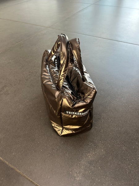 Håndtaske i skinnende brunt stof.