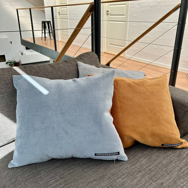 Pudebetræk i gyldenbrun, pastel blå og mørk kit. Pastel blå bagside.