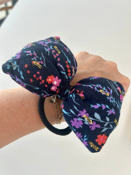 Stor fluffy sløjfe med blomster og guld detaljer.