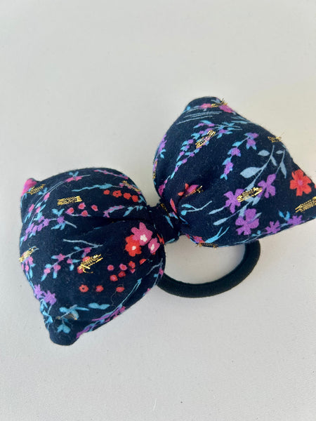 Stor fluffy sløjfe med blomster og guld detaljer.