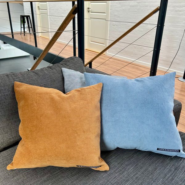 Pudebetræk i gyldenbrun, mørk kit og pastelblå, og med gyldenbrun bagside