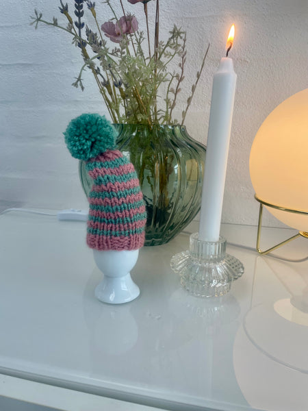 Æggevarmer ska Nissehue i lyserød og turkis strik med pom pom.