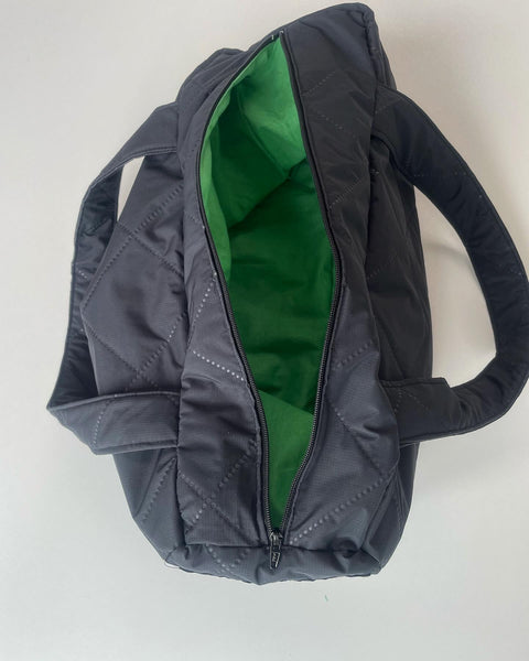 Taske i charcoal quilt med grønt foer og lommer.